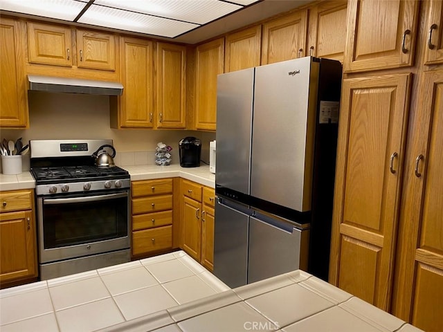 kitchen featuring appliances with stainless steel finishes, tile counters, and range hood