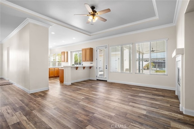 unfurnished living room with ceiling fan, crown molding, and a raised ceiling