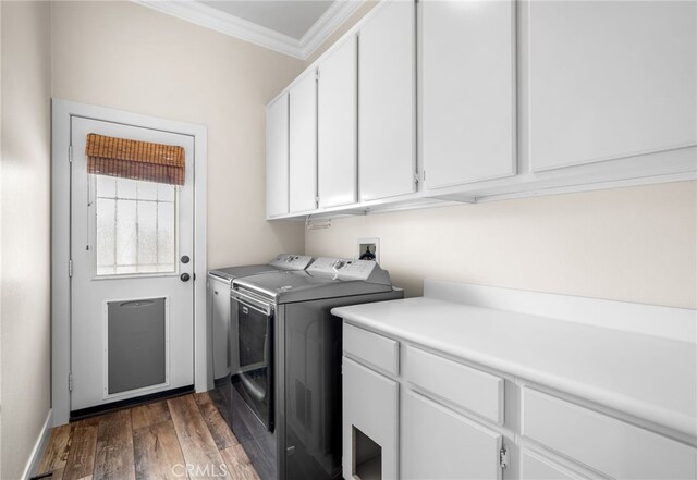 clothes washing area featuring dark hardwood / wood-style flooring, separate washer and dryer, ornamental molding, and cabinets