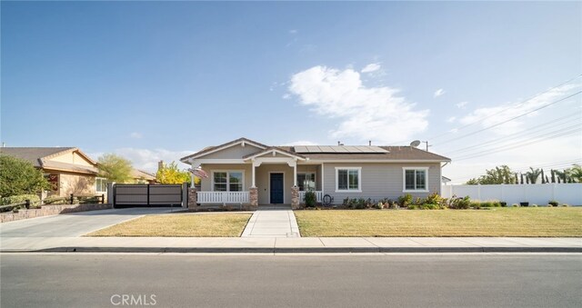 view of front of house with covered porch, solar panels, and a front lawn