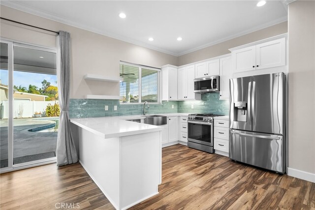 kitchen featuring kitchen peninsula, stainless steel appliances, white cabinets, and sink