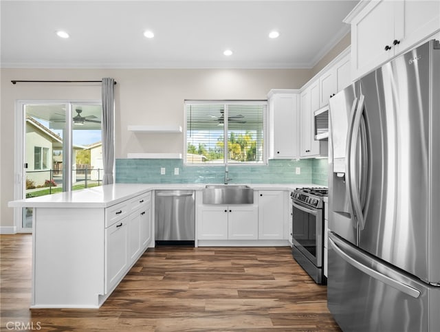 kitchen with stainless steel appliances, white cabinets, kitchen peninsula, and sink