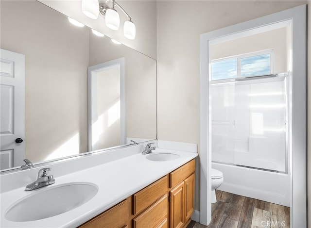 full bathroom featuring toilet, enclosed tub / shower combo, vanity, and hardwood / wood-style floors