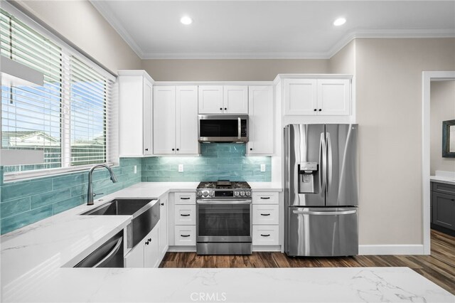 kitchen with light stone countertops, sink, stainless steel appliances, and white cabinetry