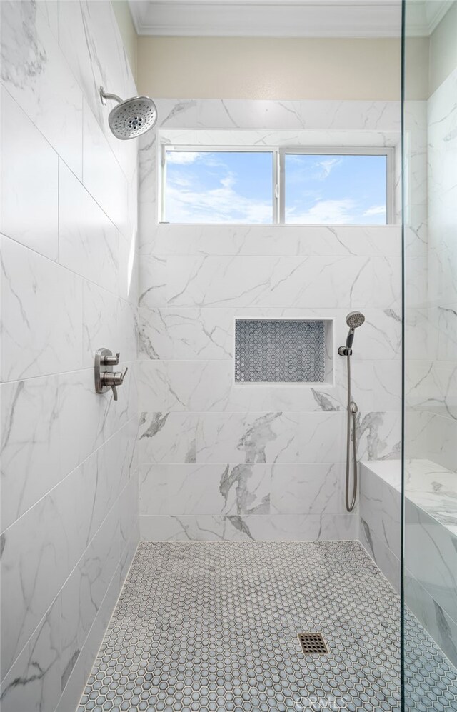 bathroom with ornamental molding and a tile shower