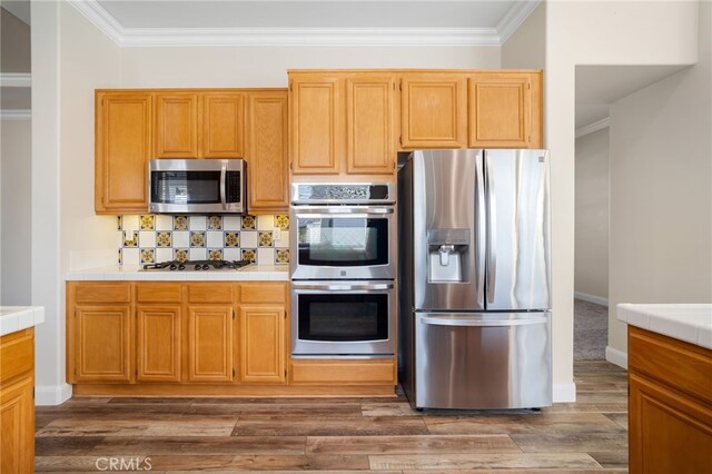 kitchen with decorative backsplash, dark wood-type flooring, crown molding, and stainless steel appliances