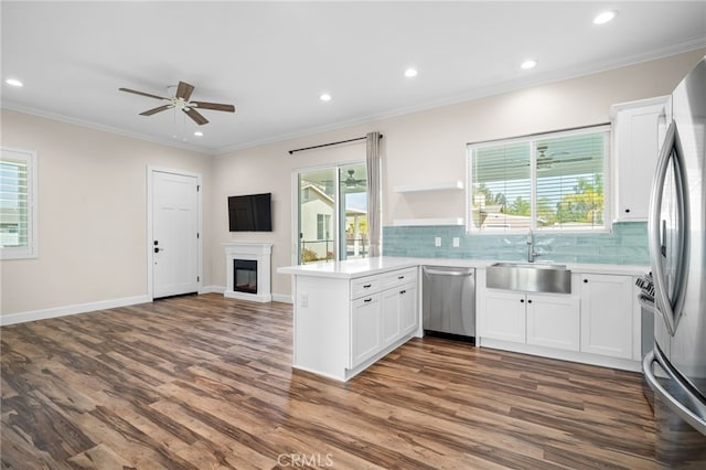 kitchen featuring ceiling fan, kitchen peninsula, sink, appliances with stainless steel finishes, and white cabinets