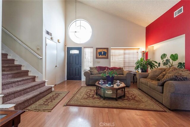 living room with high vaulted ceiling, a textured ceiling, and hardwood / wood-style flooring