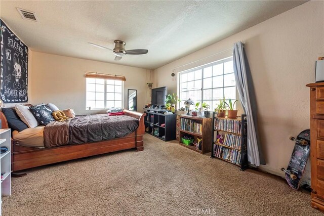 carpeted bedroom featuring ceiling fan and a textured ceiling