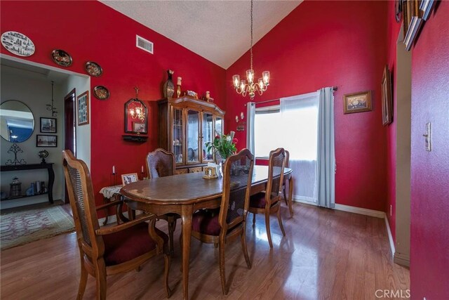 dining room featuring high vaulted ceiling, hardwood / wood-style floors, and a chandelier