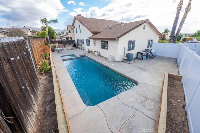 view of pool with central AC, a patio area, and an in ground hot tub