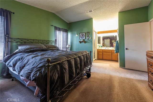 bedroom with connected bathroom, vaulted ceiling, a textured ceiling, and carpet flooring