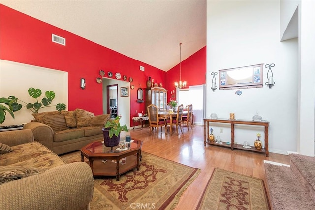 living room with high vaulted ceiling, hardwood / wood-style flooring, and a notable chandelier