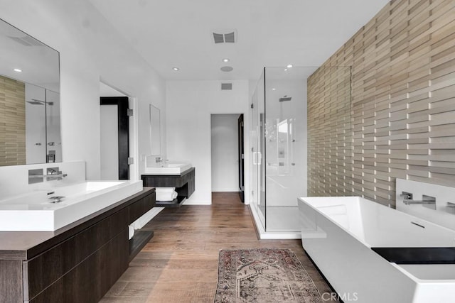 bathroom with wood-type flooring, vanity, and plus walk in shower