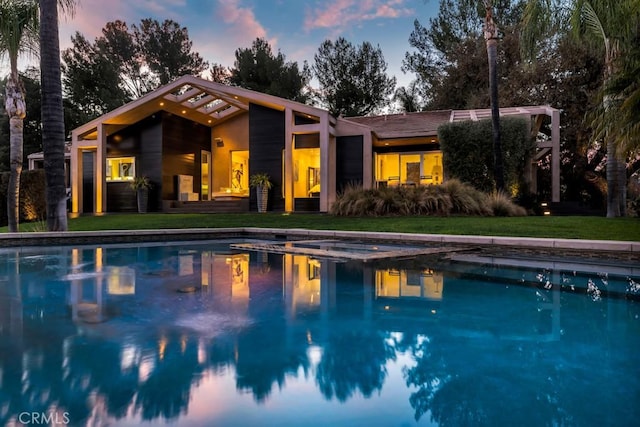 pool at dusk featuring a yard