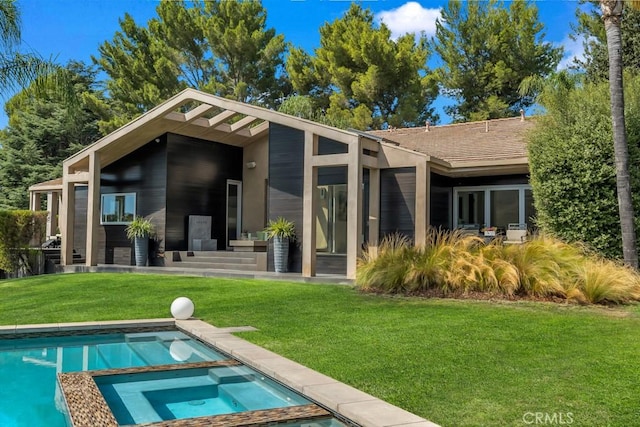 rear view of property featuring a pool with hot tub and a yard