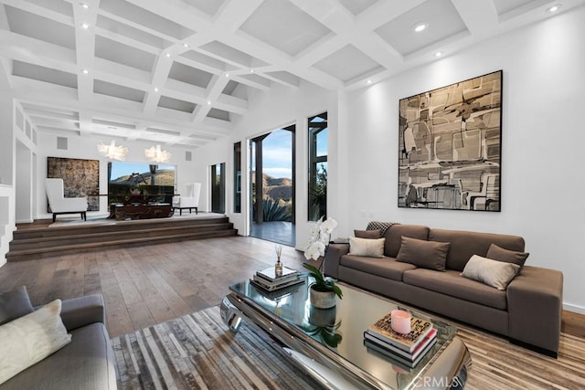 living room featuring a towering ceiling, hardwood / wood-style floors, beam ceiling, and a notable chandelier