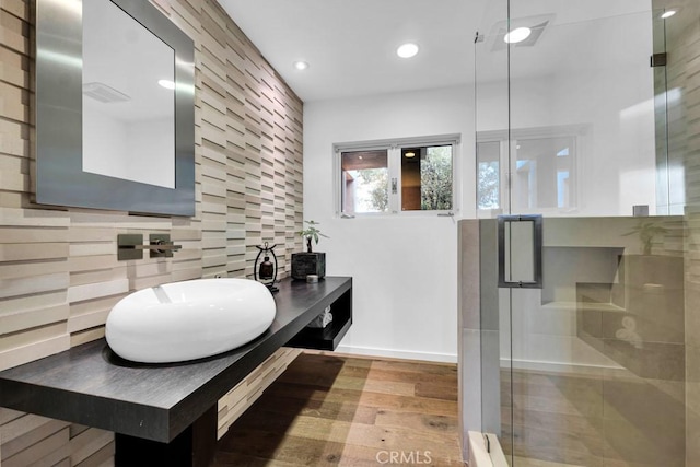 bathroom with decorative backsplash, a shower with shower door, wood-type flooring, and vanity