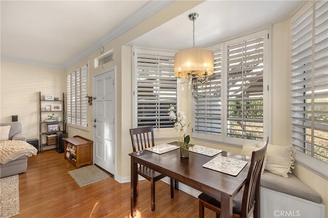 dining room with a wealth of natural light, crown molding, a chandelier, and wood-type flooring