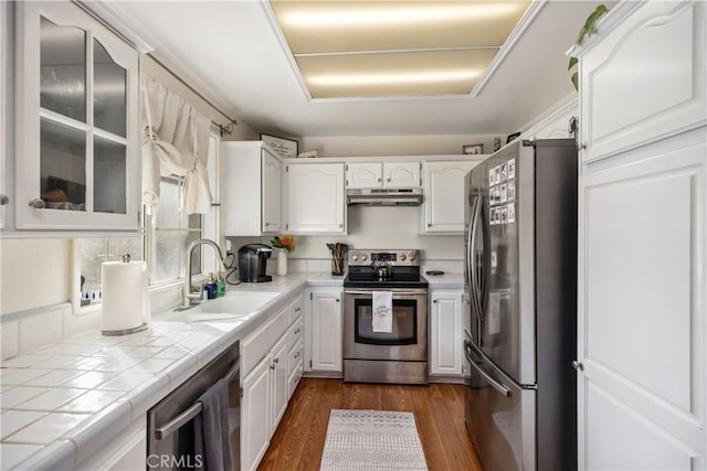 kitchen with stainless steel appliances, tile counters, and white cabinetry