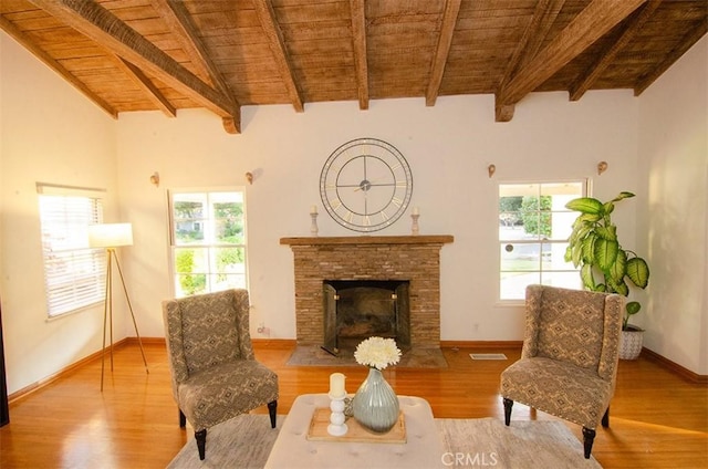 living area featuring wood ceiling, a stone fireplace, lofted ceiling with beams, and a healthy amount of sunlight