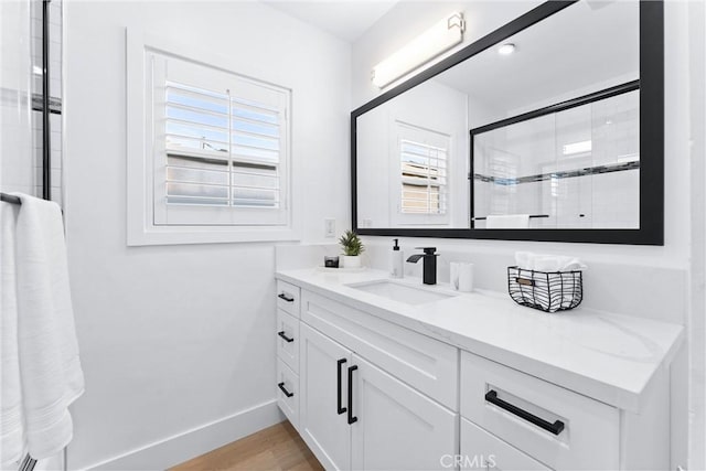 bathroom with hardwood / wood-style flooring, walk in shower, vanity, and a healthy amount of sunlight