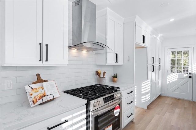 kitchen with light stone countertops, white cabinets, wall chimney exhaust hood, and high end stainless steel range oven