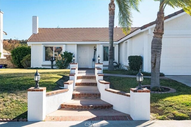 single story home with a garage and a front lawn