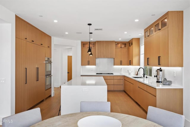 kitchen featuring pendant lighting, double oven, light hardwood / wood-style flooring, and a kitchen island