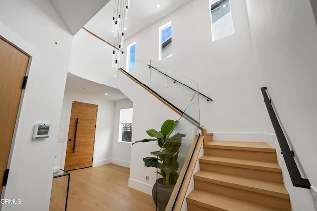 stairs featuring a high ceiling and wood-type flooring