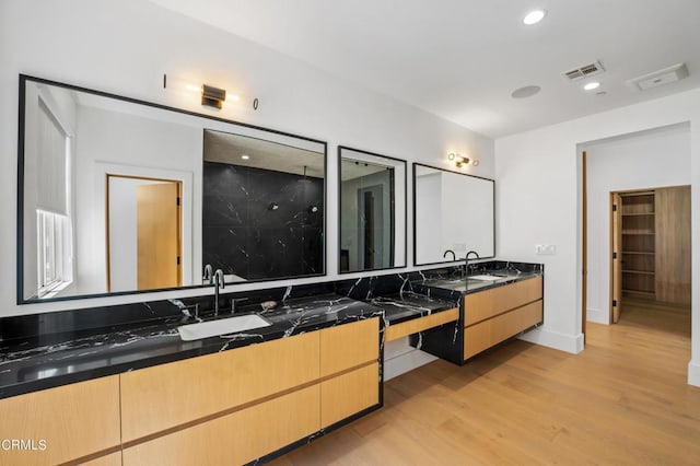 bathroom with walk in shower, vanity, and hardwood / wood-style flooring