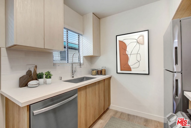 kitchen with stainless steel appliances, light hardwood / wood-style floors, sink, light brown cabinetry, and decorative backsplash