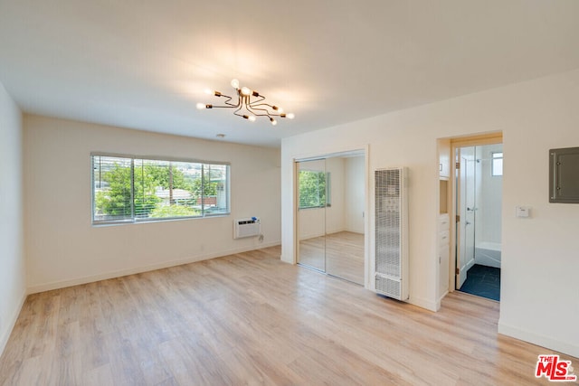 empty room featuring light hardwood / wood-style floors, an inviting chandelier, and a healthy amount of sunlight