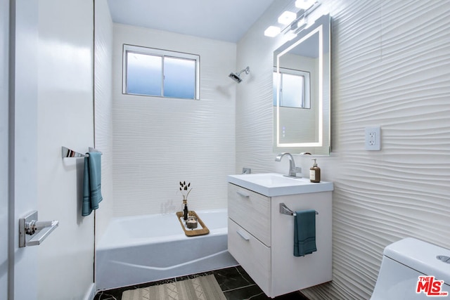 full bathroom featuring toilet, vanity, tiled shower / bath, and a healthy amount of sunlight