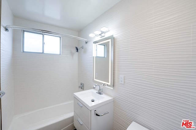 bathroom with vanity, a healthy amount of sunlight, and tiled shower / bath