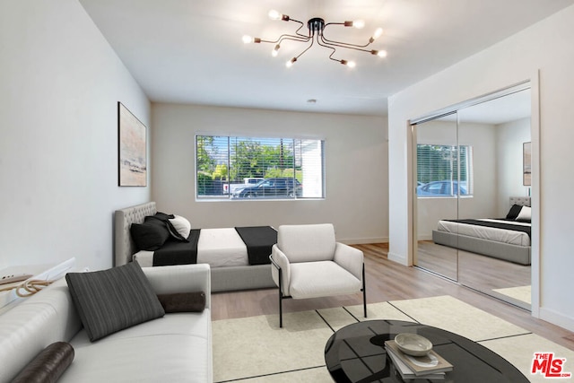 living room with a healthy amount of sunlight, an inviting chandelier, and light hardwood / wood-style flooring