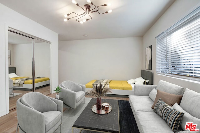 living room with light hardwood / wood-style flooring, a healthy amount of sunlight, and an inviting chandelier