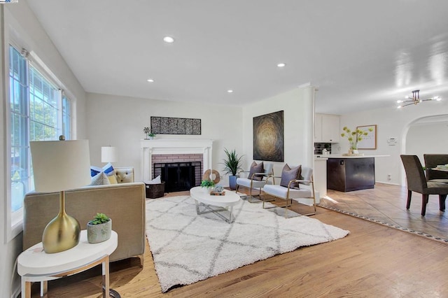 living room with light hardwood / wood-style floors, an inviting chandelier, and a fireplace