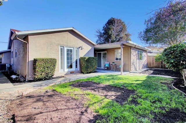 back of house with central AC and a lawn