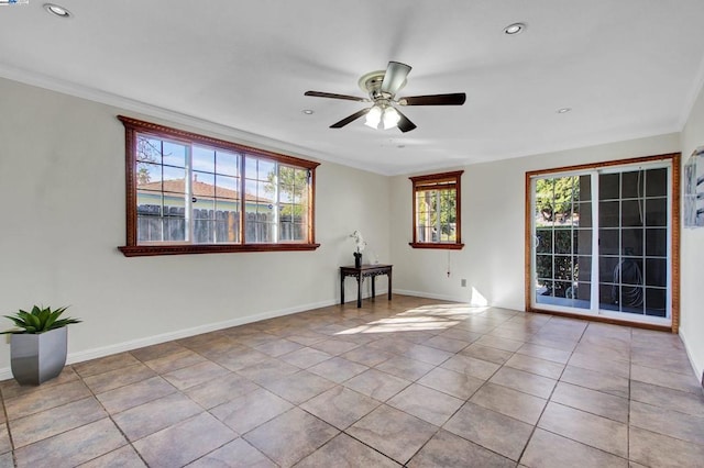 tiled empty room featuring ceiling fan and crown molding