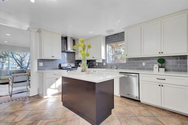 kitchen with stainless steel dishwasher, white cabinets, sink, and wall chimney exhaust hood