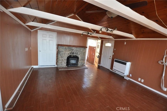 unfurnished living room featuring dark wood-type flooring, heating unit, wooden walls, and lofted ceiling with beams