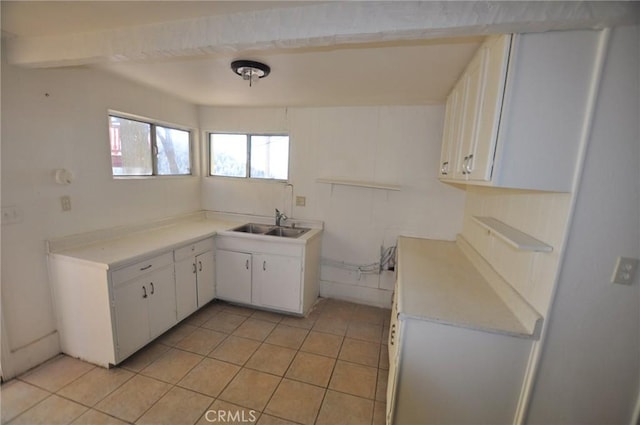 kitchen featuring light tile patterned floors, sink, and white cabinetry