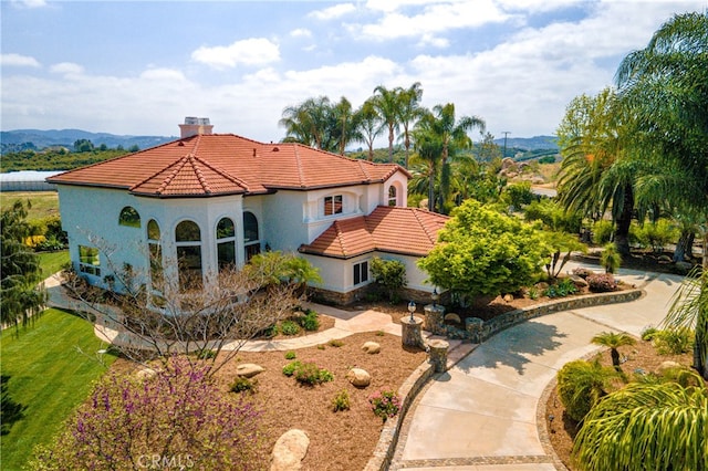 view of front of house featuring a tile roof, a chimney, and stucco siding