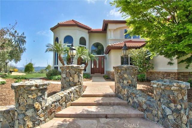 mediterranean / spanish house with a tiled roof and stucco siding