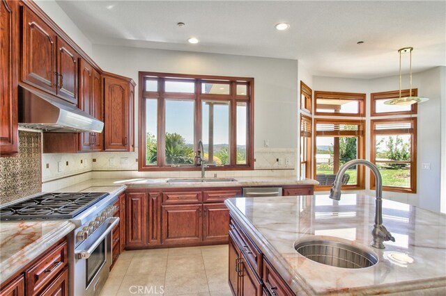 kitchen with sink, hanging light fixtures, stainless steel appliances, light tile patterned floors, and light stone counters