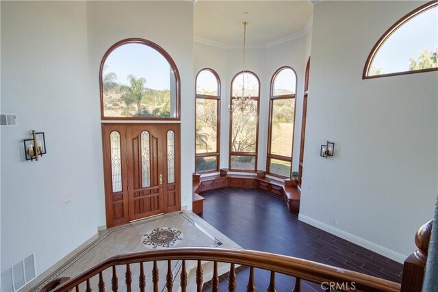 foyer entrance with plenty of natural light, crown molding, and a towering ceiling