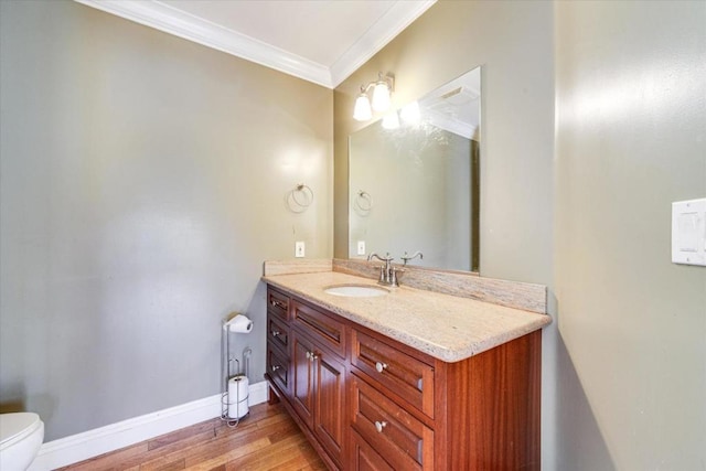 bathroom with toilet, vanity, crown molding, and hardwood / wood-style floors