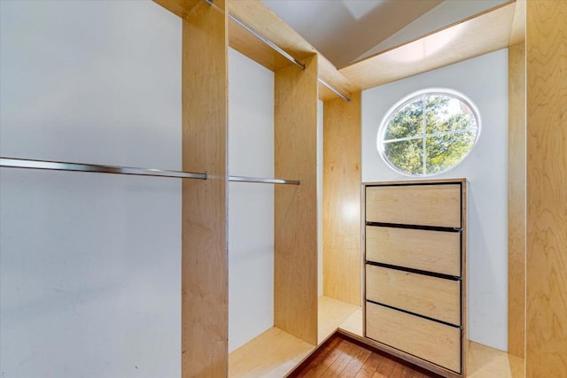 bathroom with a shower, wood-type flooring, and vaulted ceiling