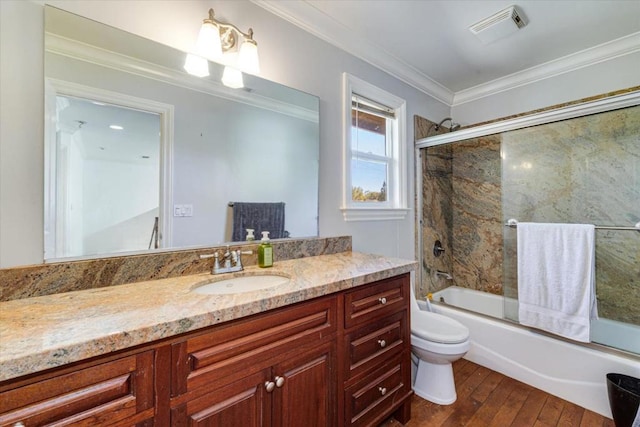 full bathroom featuring toilet, vanity, hardwood / wood-style floors, ornamental molding, and shower / bath combination with glass door